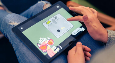 Kind spielt das Mobile Game KatzeQ auf einem Tablet, Figur sichtbar auf dem Display.